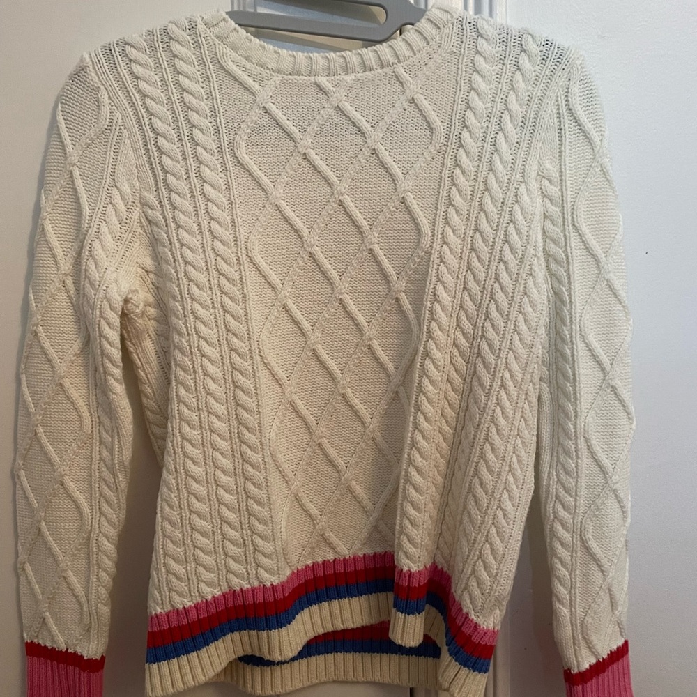 M.E.N.U white sweater with rainbow lining around bottom and bottoms of sleeves.